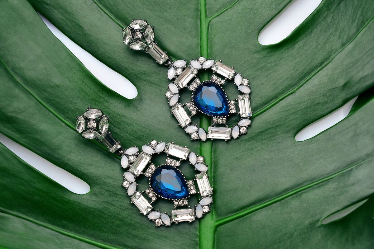Blue gemstone earrings photographed on a green leaf before background removal